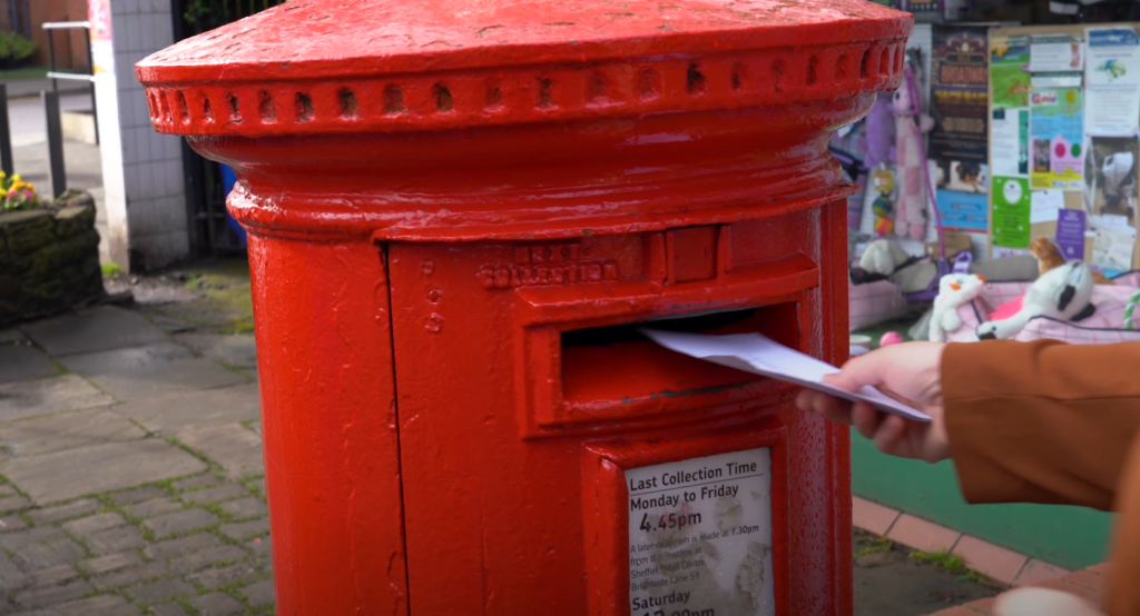 Ruth Milsom posting a letter in a Royal Mail postbox in Crosspool